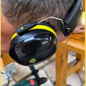 Man using drill while wearing yellow ear protection earmuffs