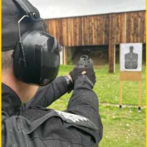 Man practices at the range while wearing gray ear protection earmuffs